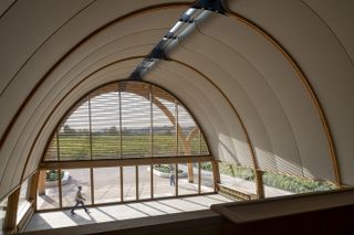 Bodegas Faustino Winery seeing its rounded roof and ceiling, The design reinterprets the winery as a whole andcreates a stronger connection between theexisting cellars and the surrounding vineyard