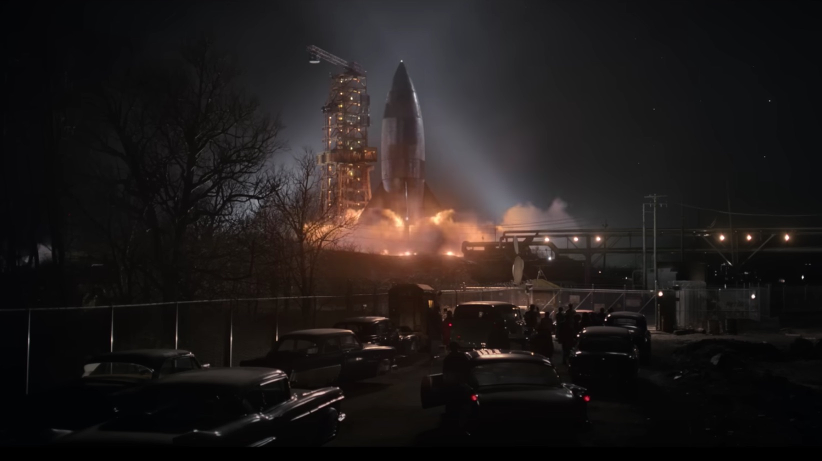 Un cohete se lanza a la noche rodeado de decenas de coches de los años 50