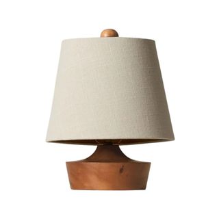 A table lamp with a beige lampshade and a dark wooden base