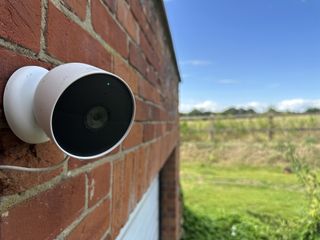 A Google Nest Camera on a red brick house with fields in the background