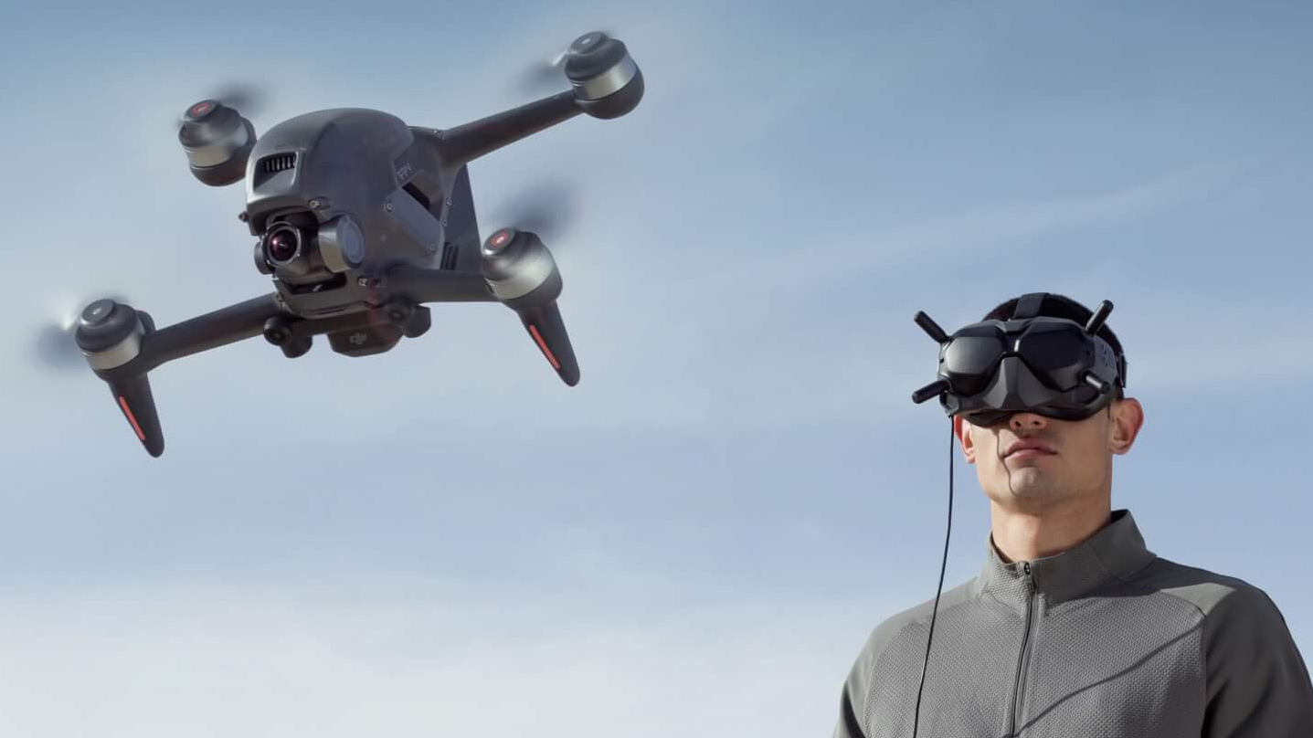 A man wearing the DJI Goggles V2 headset while flying the DJI FPV drone