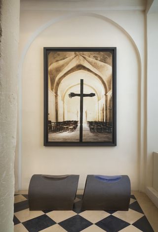 Interior of Pierre Yovanovitch showroom in Paris with white walls, artwork with a cross, and two benches