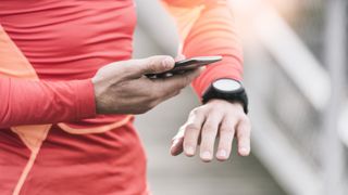 man in running gear with smartwatch checking his phone