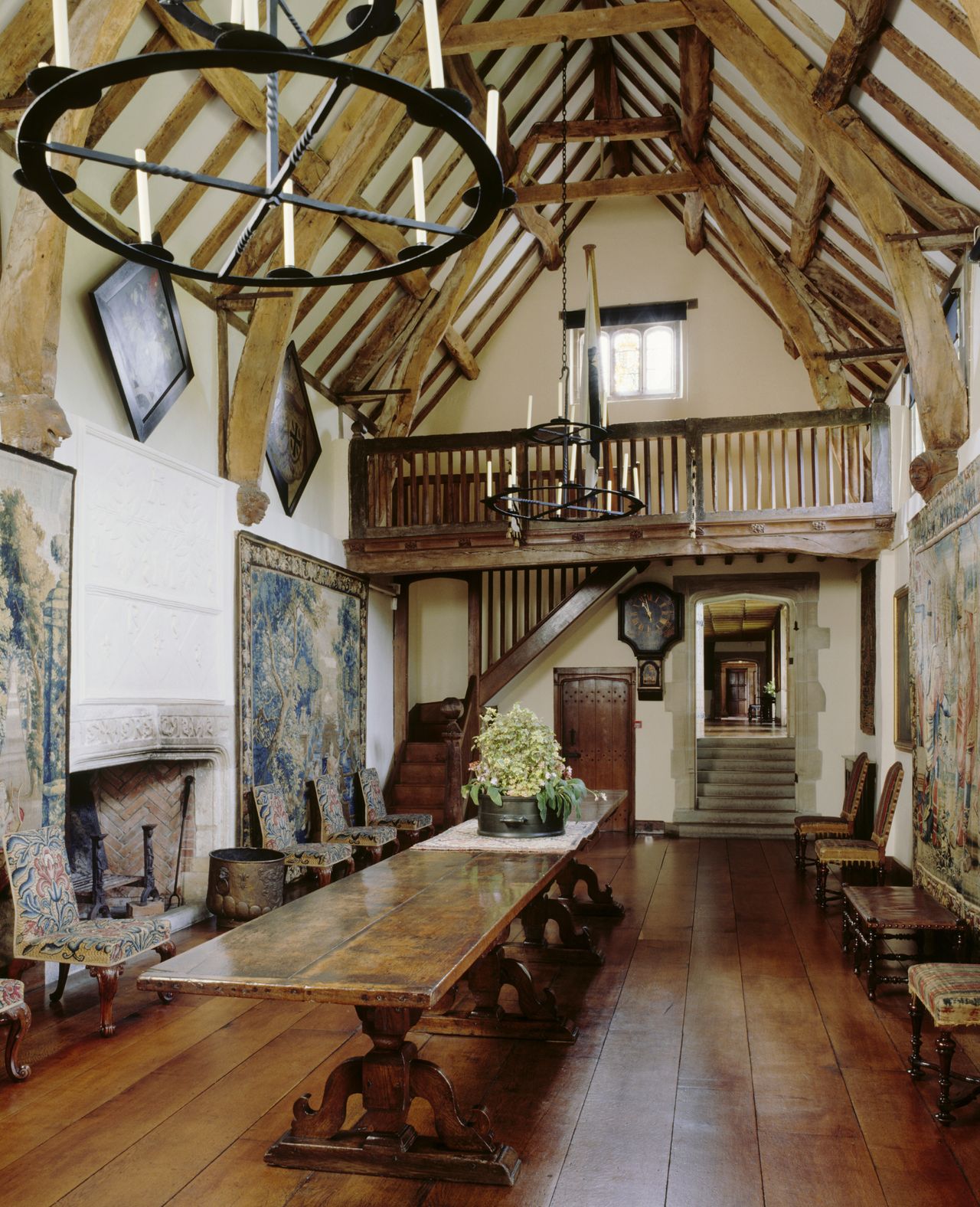 The Great Hall at Packwood House showing the long oak refectory table, fireplace and plaster overmantel, hatchments and timber ceiling. A suite of George I walnut chairs stand around the room.
