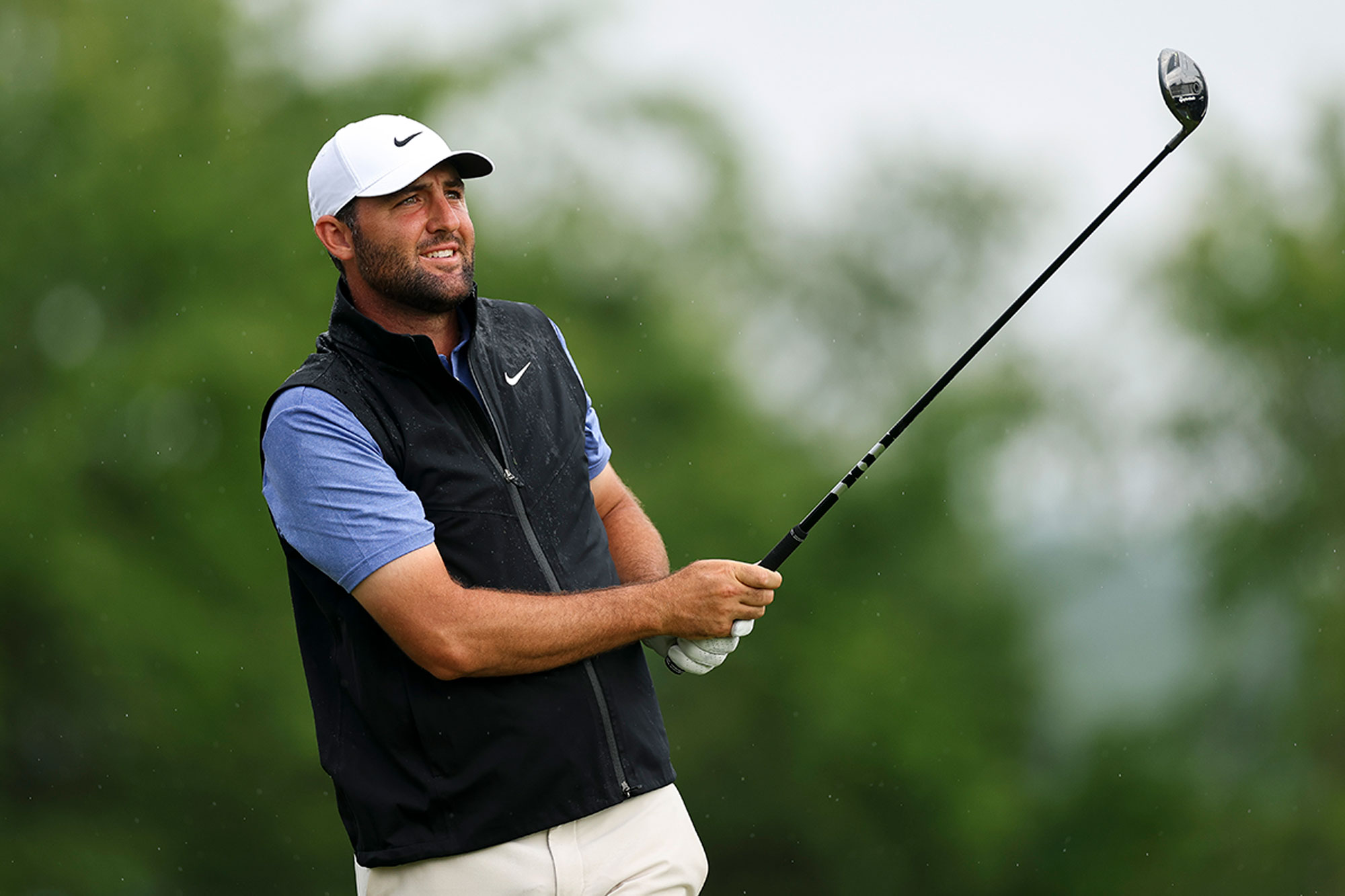Scottie Scheffler holding his fairway wood towards the fairway and watching his ball flight after hitting a shot with a wood on the golf course