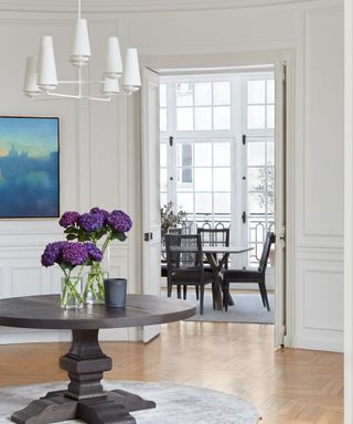 white paneled hallway with round table and view to dining room