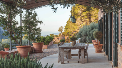 a covered outdoor patio with a wooden dining table and chairs overlooking a scenic view