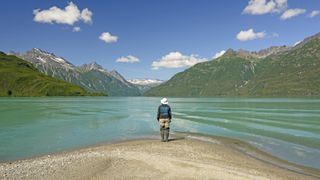 A hiker standing at the water's edge in Lake Clark National Park Alaska