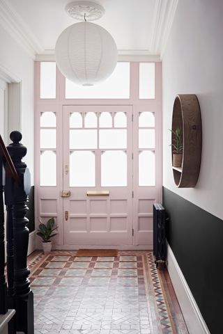 Hallway with tile floor, lower wall in black and upper in white, and front door painted in pale pink