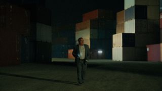 Joaquin searches among the shipping containers at night as seen in Iron Reign episode 2.