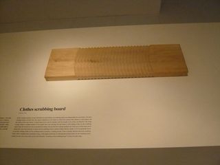 A wooden Chinese scrubbing board mounted on a white surface alongside a title and description