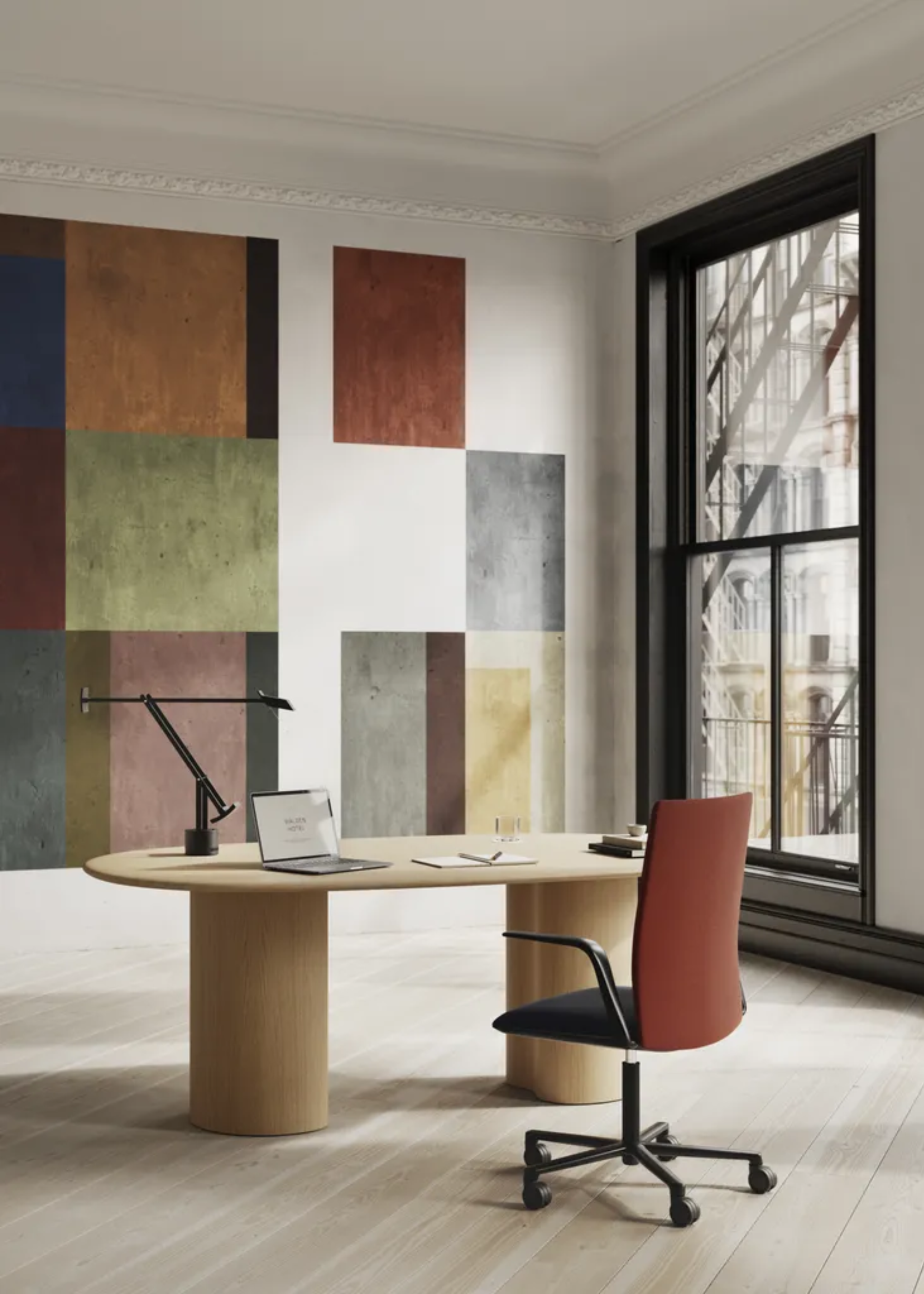 A bright home office with a color-blocked accent wall, a wood table with a desk lamp, a swivel chair, and an open laptop by a book with a pen