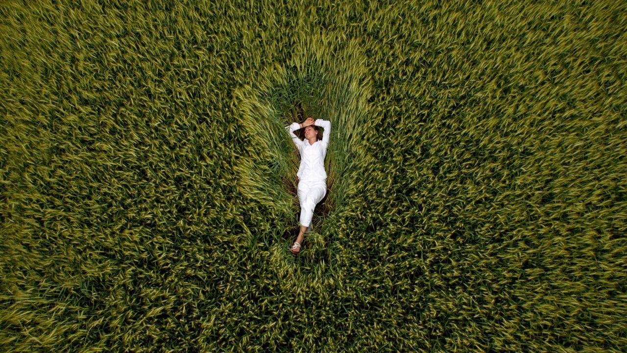 A woman practicing NSDR (no sleep deep rest) in the grass