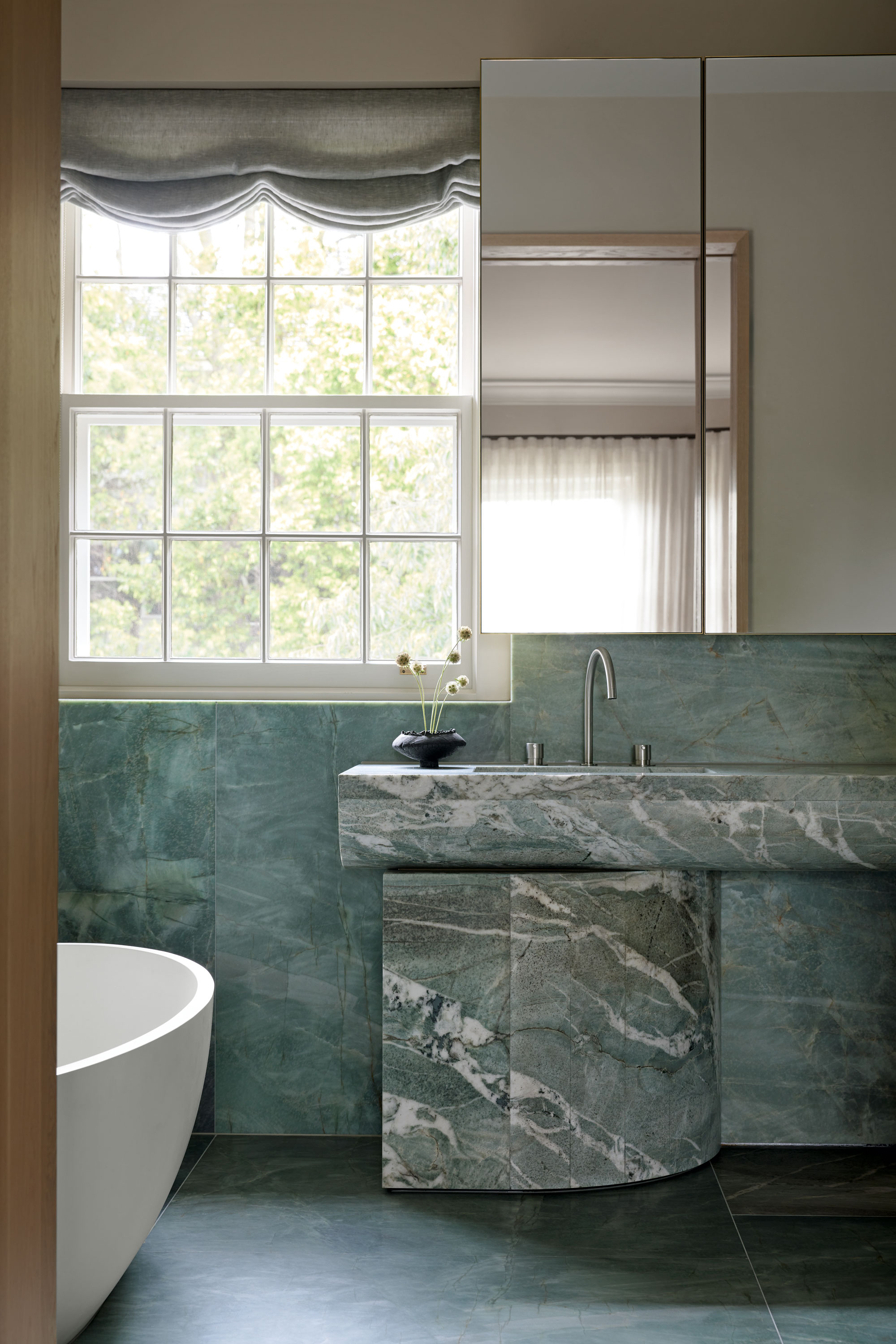 a blue bathroom with a blue stone sink and window with a roman blind above