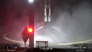 A black and white spacex falcon 9 rocket first stage sits on the deck of a ship at sea.