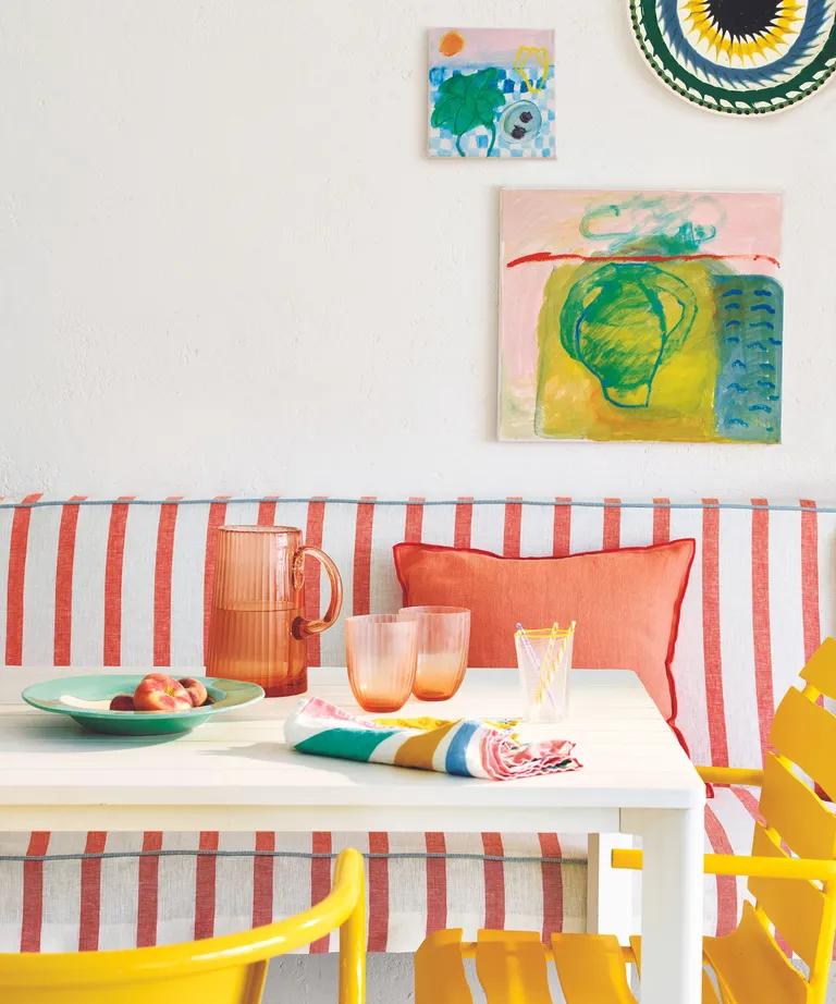 Pink and white striped dining bench, white table, yellow chairs