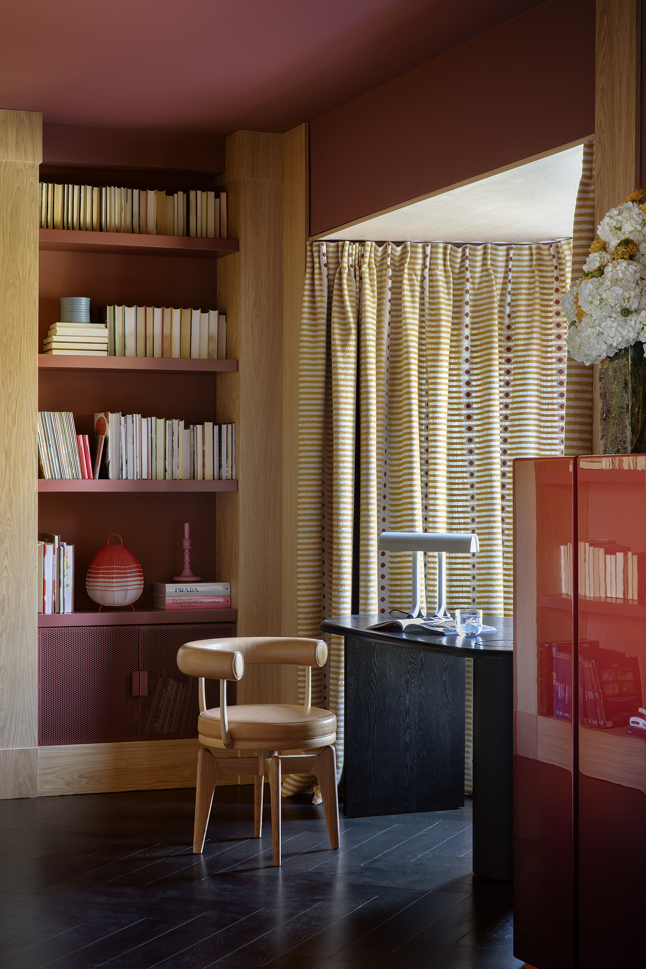 A series of interior shots depicting theatrically decorated spaces with bold lacquered red, chrome, patterned, and sculptural accents.