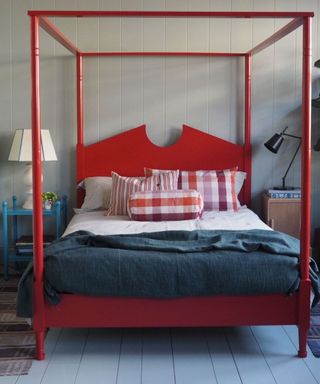 Pared back bedroom with a statement red four poster bed