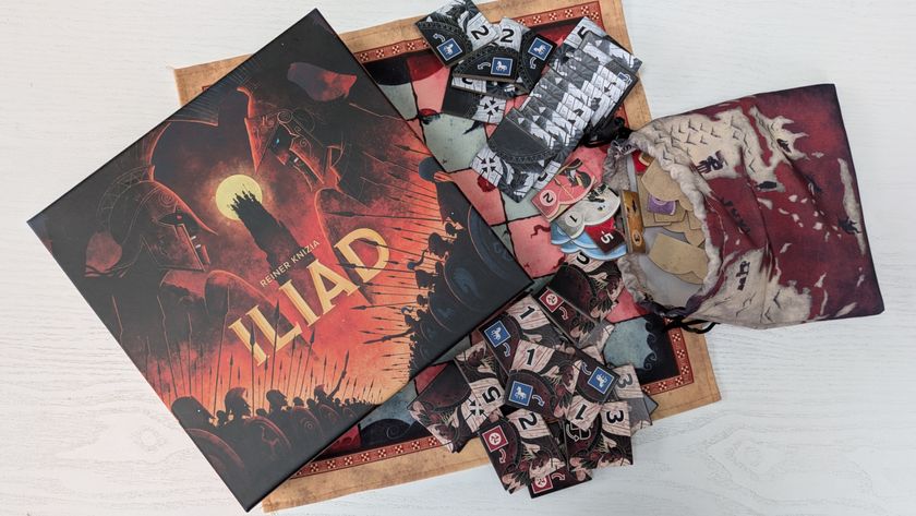 Iliad box, tiles, bag, and board on a white wooden surface