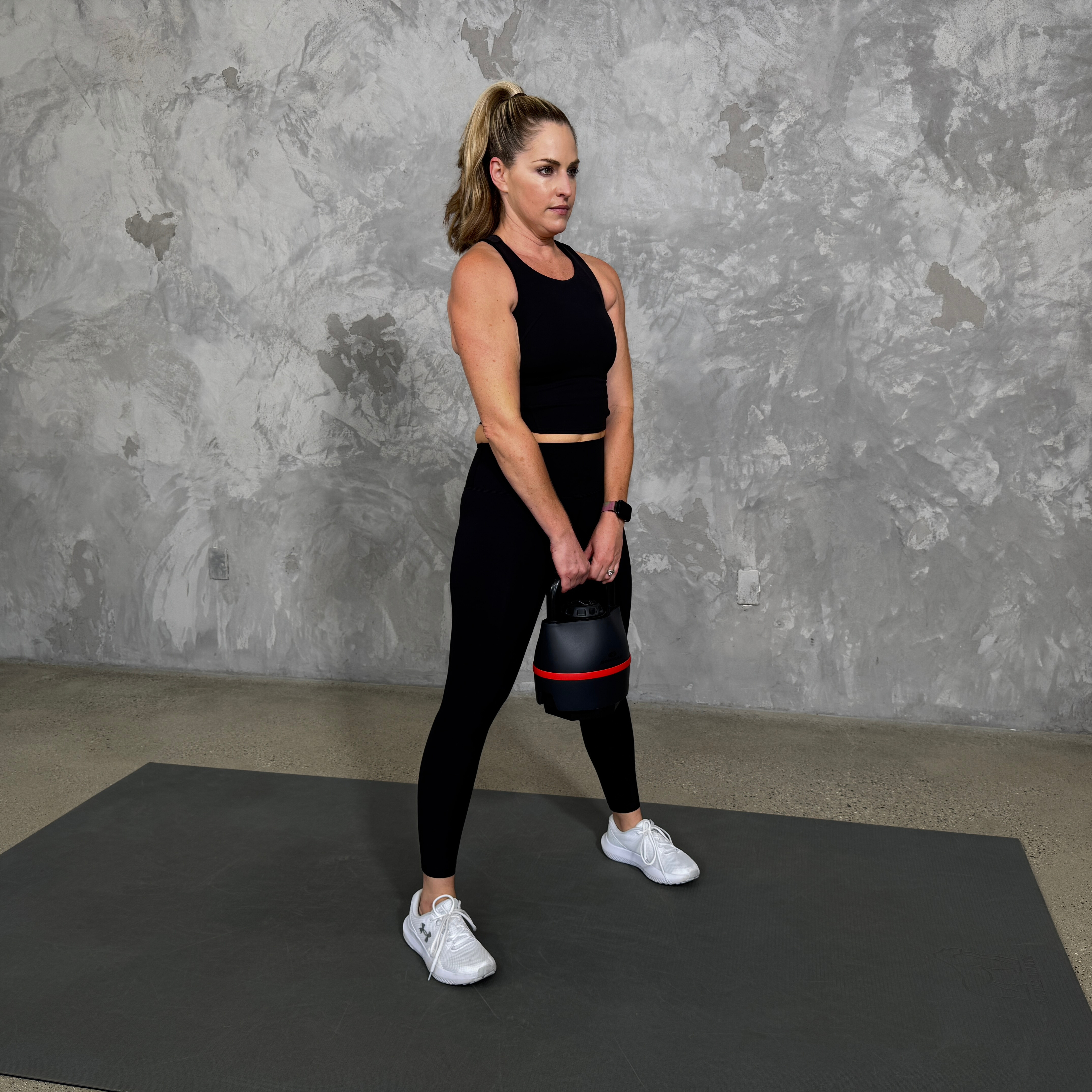 Woman in blue sportswear exercises with kettlebell