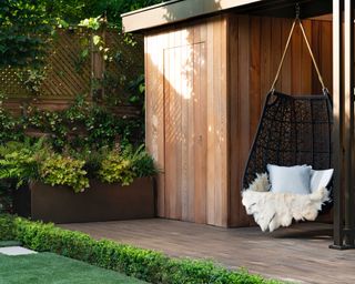 large corten steel planter and hanging seat in luxurious garden area