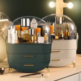 Two multiple tier makeup organizers on a cabinet in green and cream.