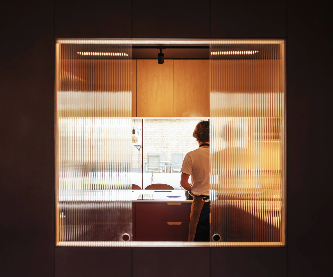 View from behind the kitchen through glass with the back of someone behind a counter