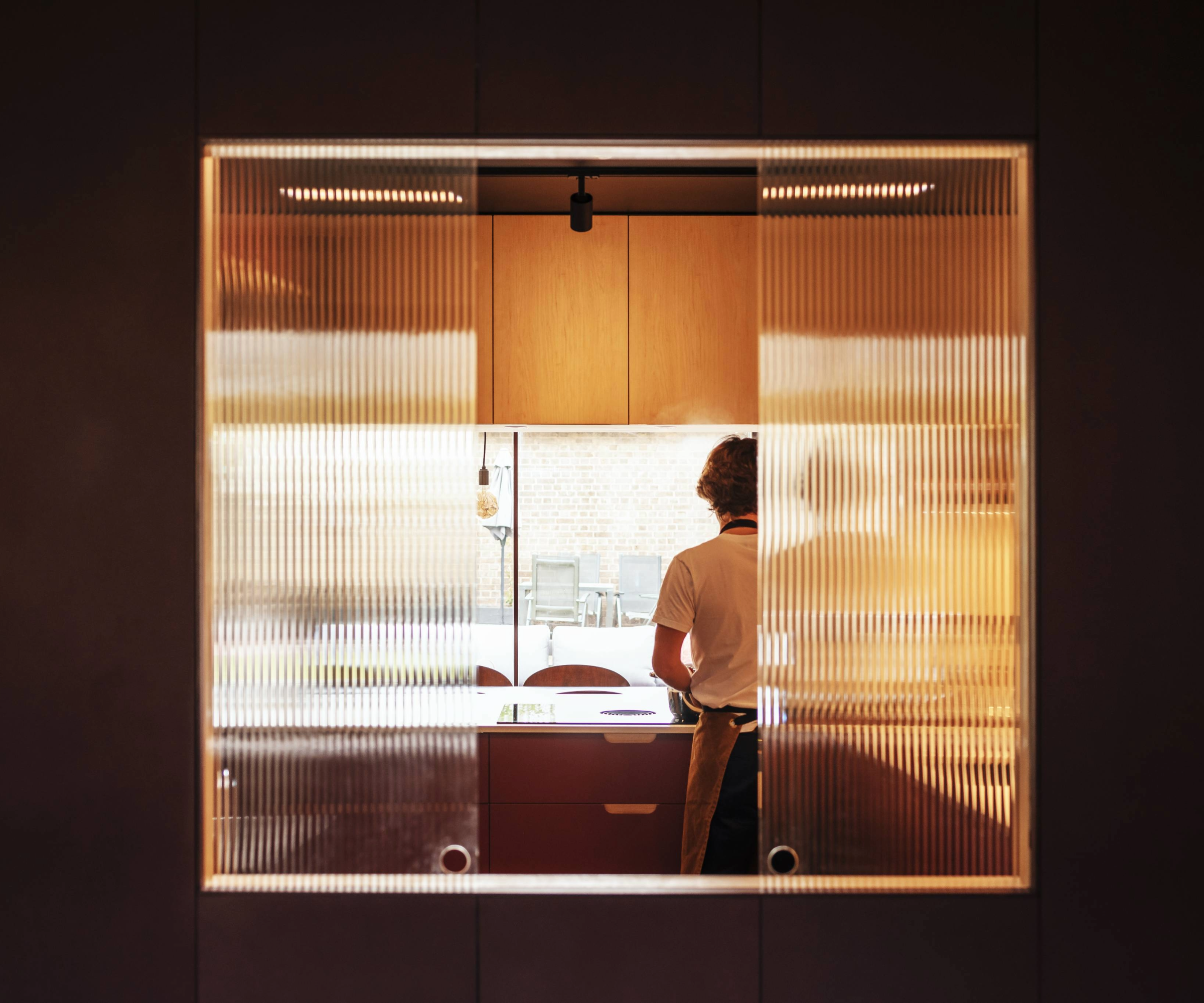 View from behind the kitchen through glass with the back of someone behind a counter