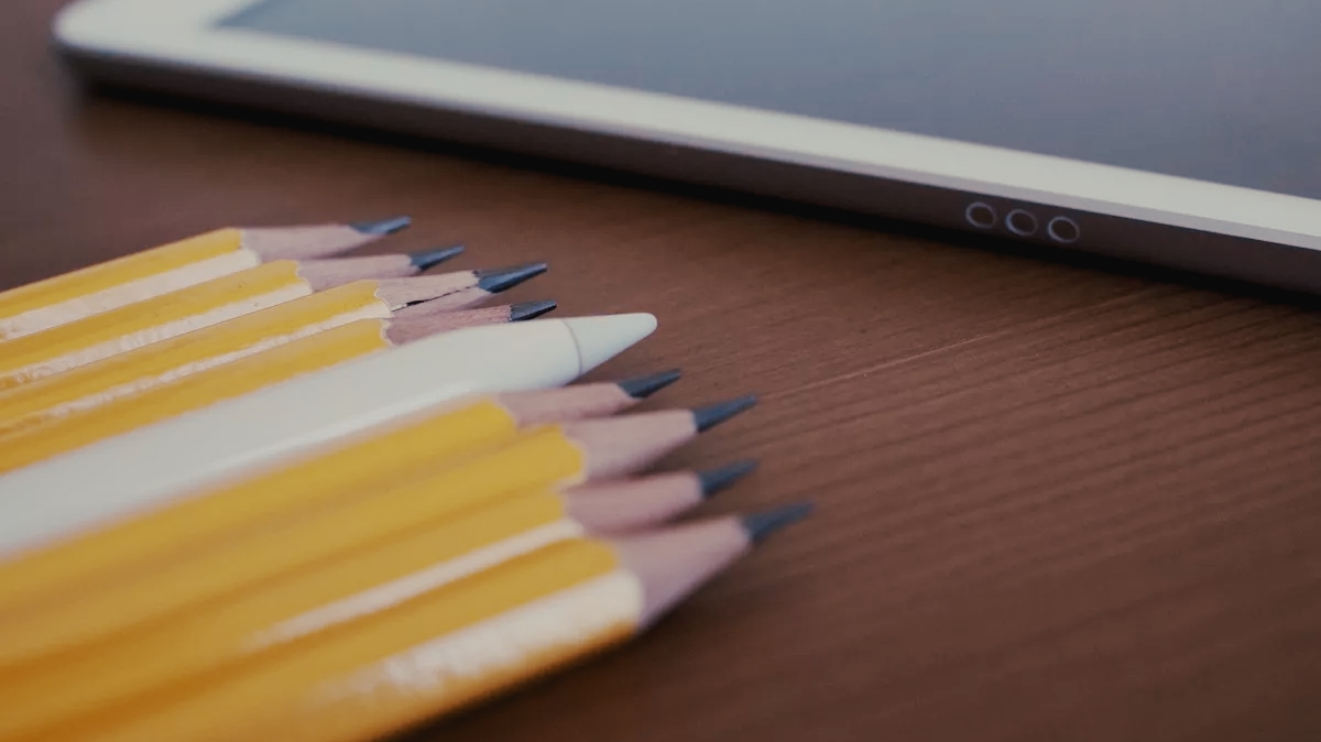 Apple Pencil лежит рядом с деревянными карандашами.