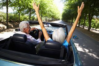 An older couple happily takes a spin in a convertible. 