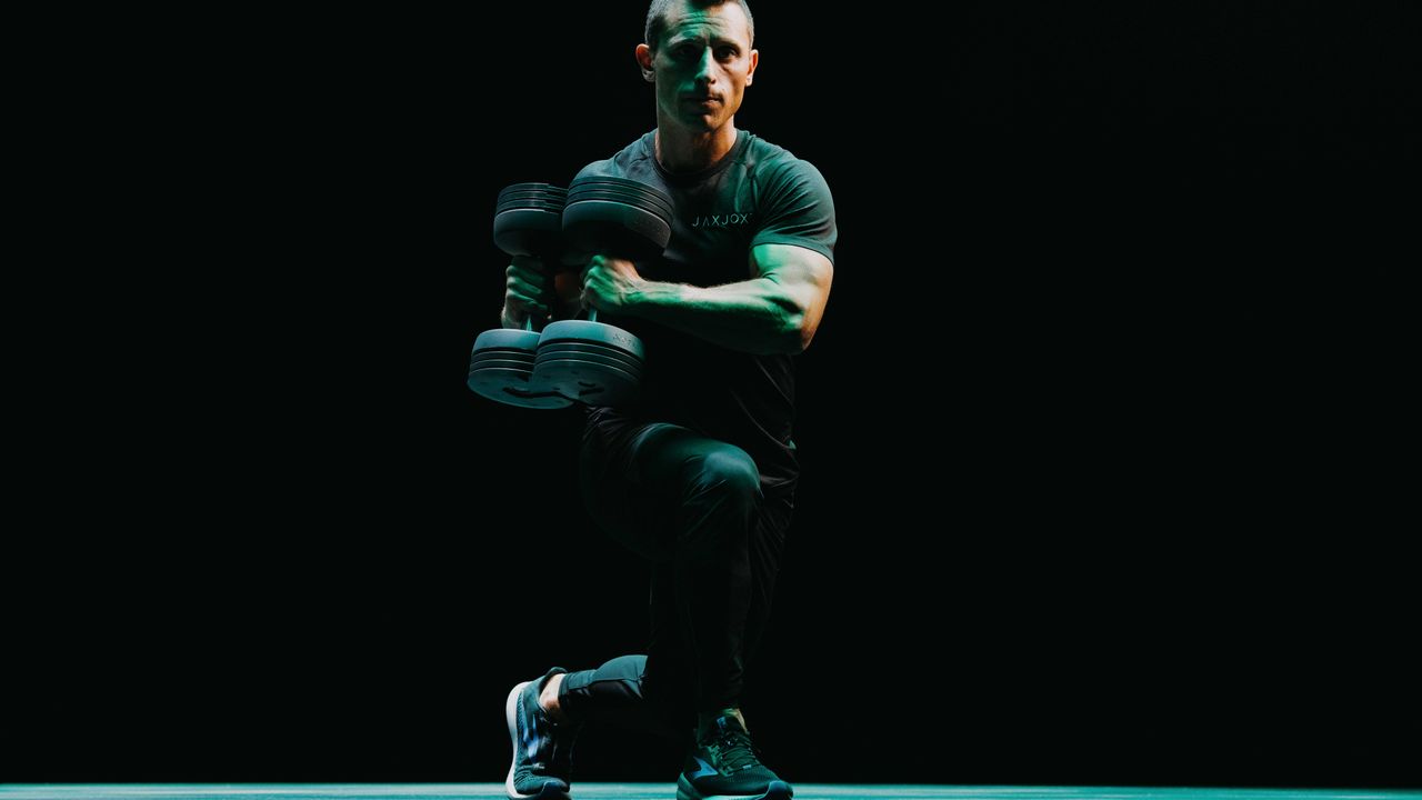 Person doing lunges with side twists using the JAXJOX DumbbellConnect adjustable dumbbells in a studio