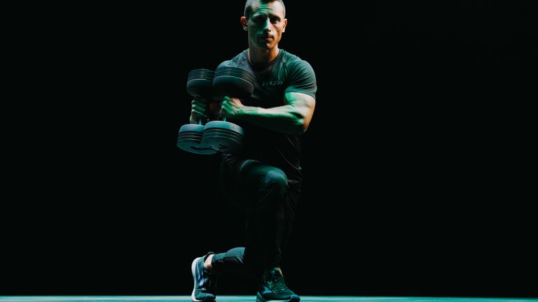 Person doing lunges with side twists using the JAXJOX DumbbellConnect adjustable dumbbells in a studio