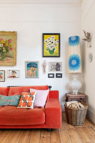 A living room with bright Paprika red velvet sofa and framed wall art decor