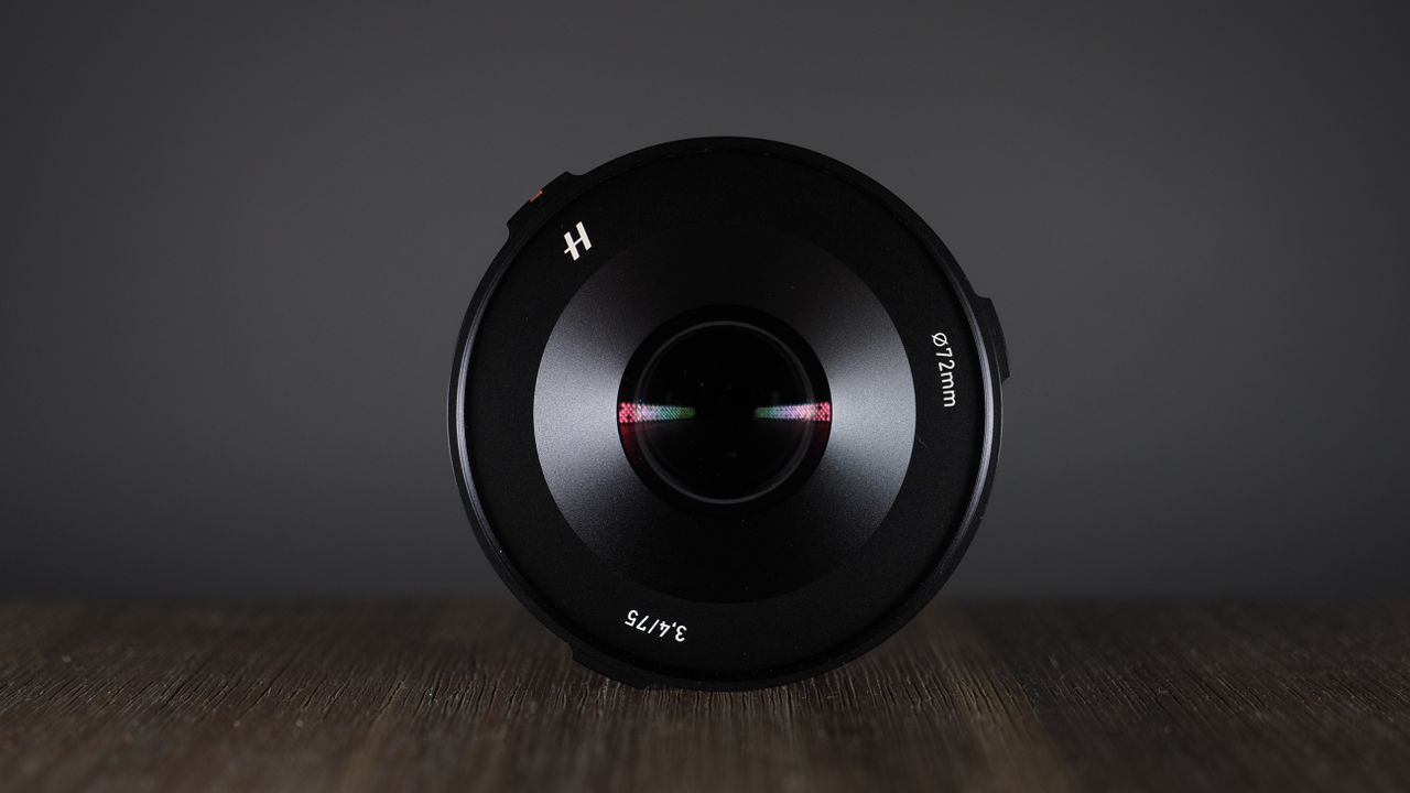 Hasselblad XCD 75P lens, on a wooden surface, against a dark background