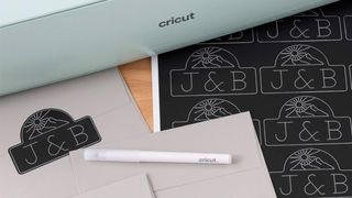 The best Cricut pens; a pen on a table with papers and a Cricut machine