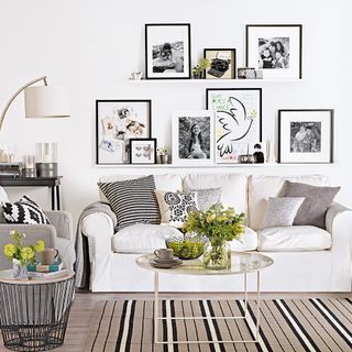 white living room with frames and potted plant on table