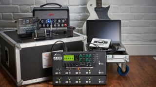 Lots of music gear on a flight case including multi-effects pedal, guitar amp, electric guitar, and more