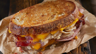 A sandwich filled with cooked turkey leftovers, cheddar cheese and bacon