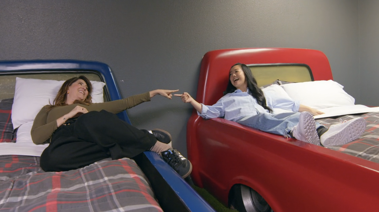 D'Arcy Carden and Sherry Cola pointing at each other lying down in car-shaped beds in Wild Vacation Rentals