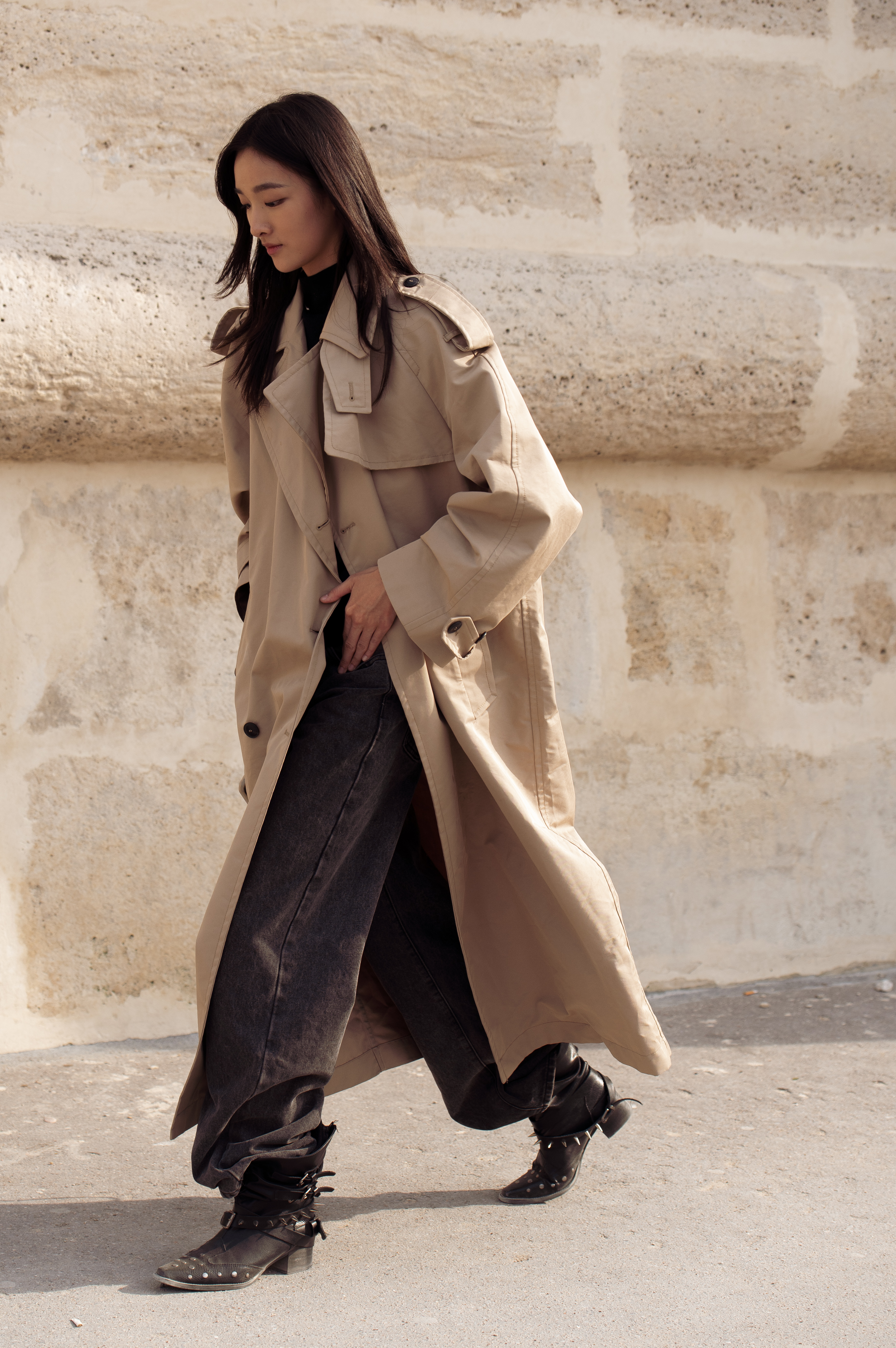 PARIS, FRANCE - OCTOBER 01: A guest wears a beige oversized trench coat layered over black wide-leg jeans, styled with black pointed studded boots outside Dior show during the Womenswear Spring Summer 2026 as part of Paris Fashion Week on October 01, 2025 in Paris, France. (Photo by Raimonda Kulikauskiene/Getty Images)