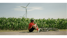 A picture of Mathieu Belanger-Barrette sitting alongside his bike in front of a cornfield in The Seven Phases of Madness