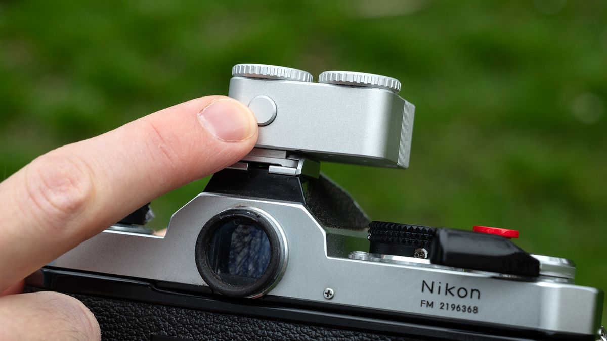 Close-up of TTArtisan Light Meter II on a Nikon FM with finger pressing the reading button