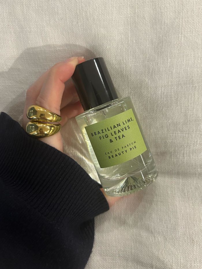 Junior beauty editor Grace Lindsay holding a Beauty Pie perfume on a white linen background