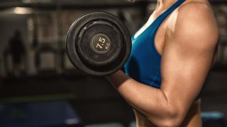 Cropped shot of a fitness woman holding a dumbbell and performing a bicep curl