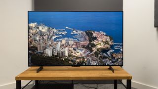 LG C4 42-inch OLED TV on wooden TV bench with panoramic aerial view on screen