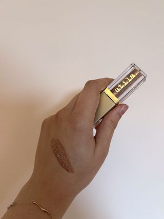 Mica Ricketts showing swatch of Stila Glitter & Glow Liquid Eye Shadow Bronzed Bell