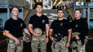 Steve Kapala, Jesse Wang, Vlad Link and Laddy Aldridge of the U.S. Navy dive medical team pose aboard the USS John P. Murtha ahead of Artemis 2 recovery operations in the Pacific Ocean.