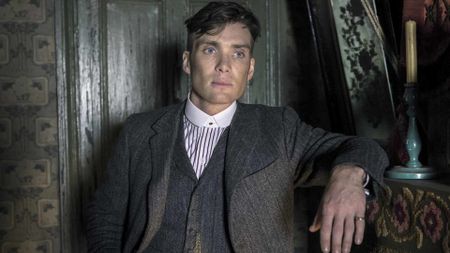 Cillian Murphy leans on a fireplace with his left arm