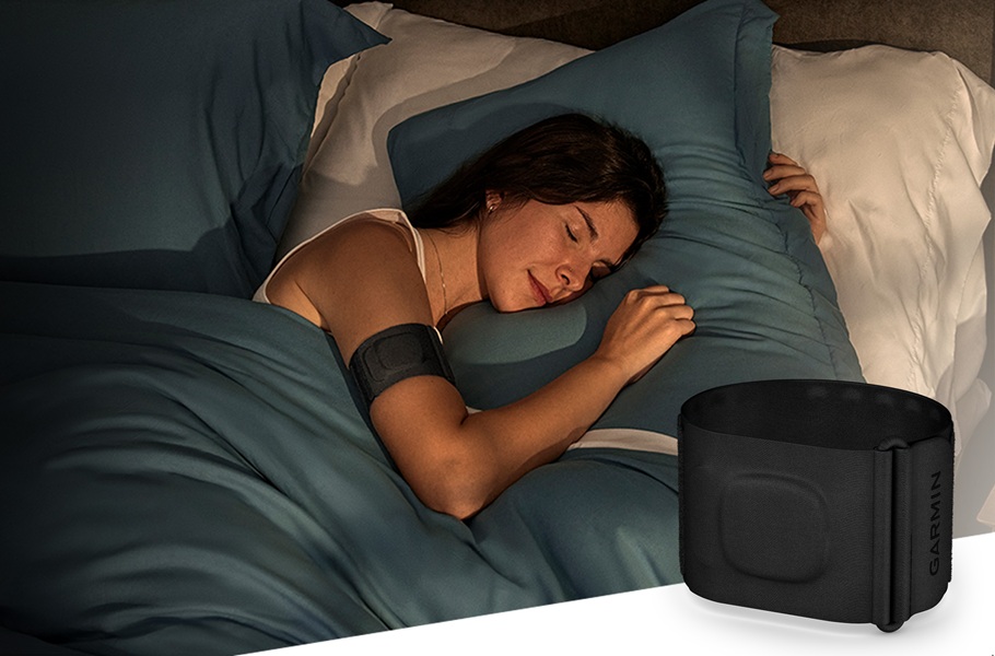 A model is wearing the Garmin Index Sleep Monitor on her right arm while she sleeps.