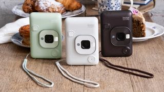 Three Fujifilm Instax mini LiPlay instant cameras in the green, white and bronze colorways